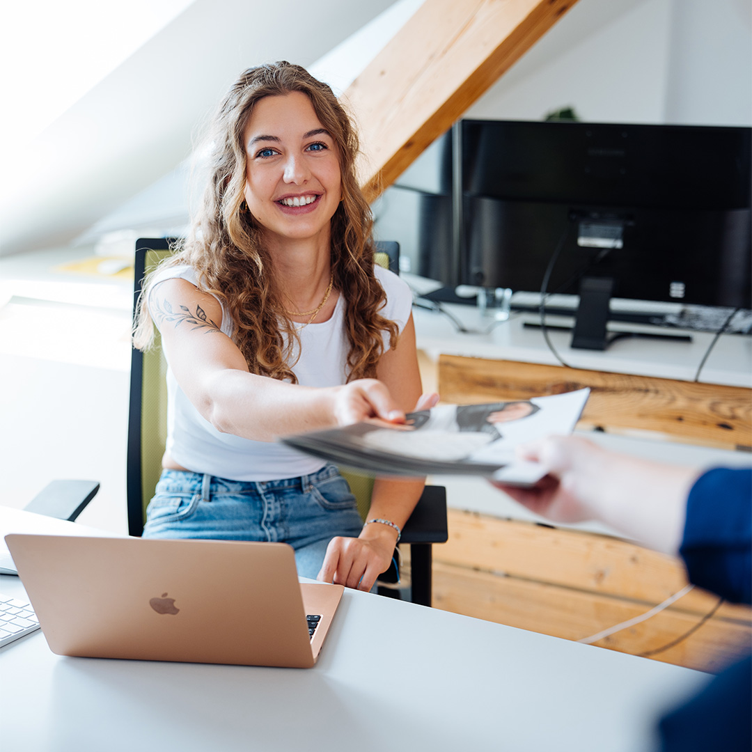 KG-180-1 Frau übergibt Dokument in der Online Marketing Agentur